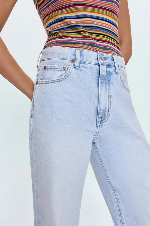 Person wearing a colorful striped top and light blue jeans on a plain background