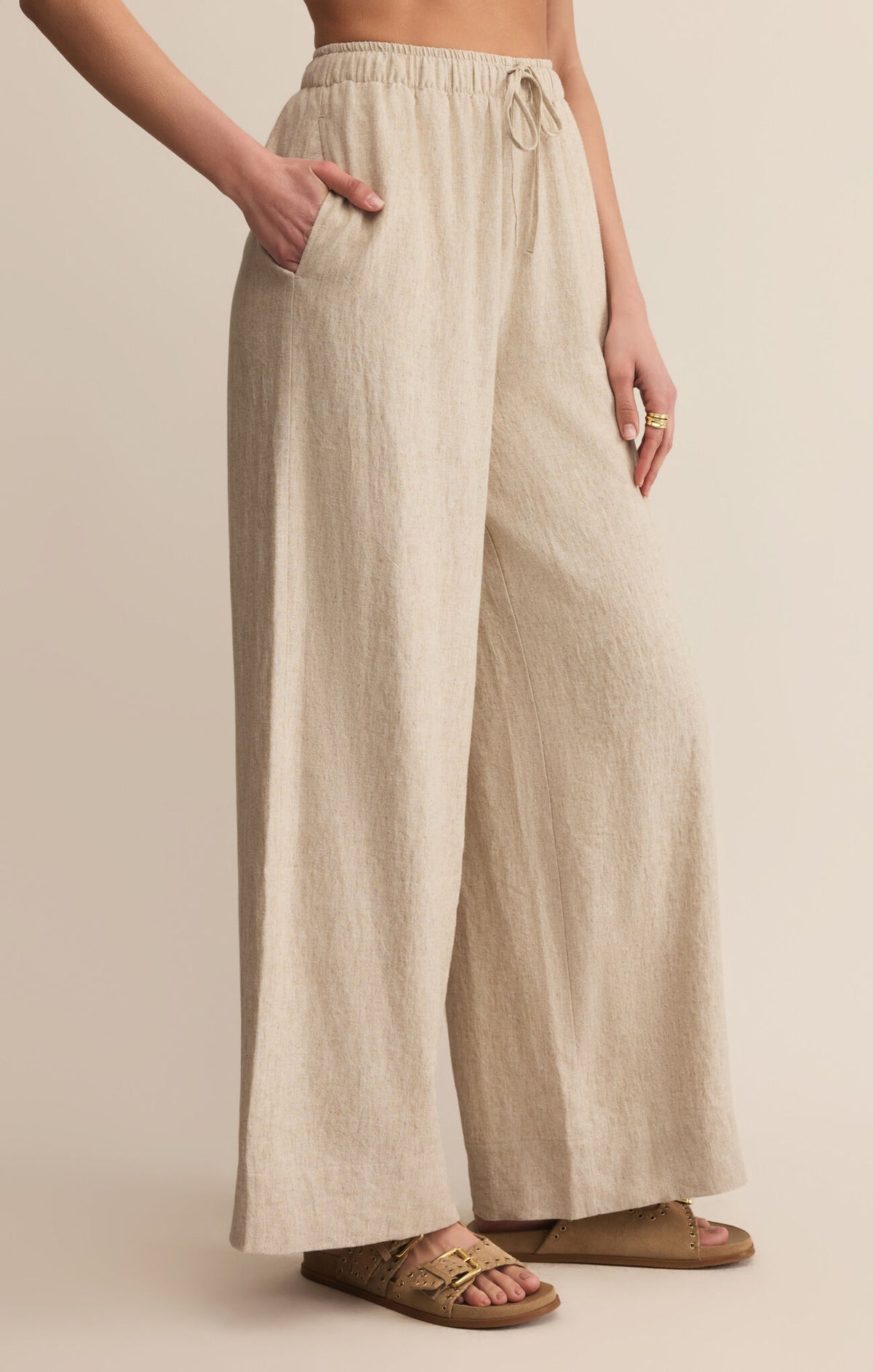 Beige linen pants worn by a person on a beige background