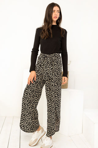 Woman wearing a black top and patterned pants on a white background