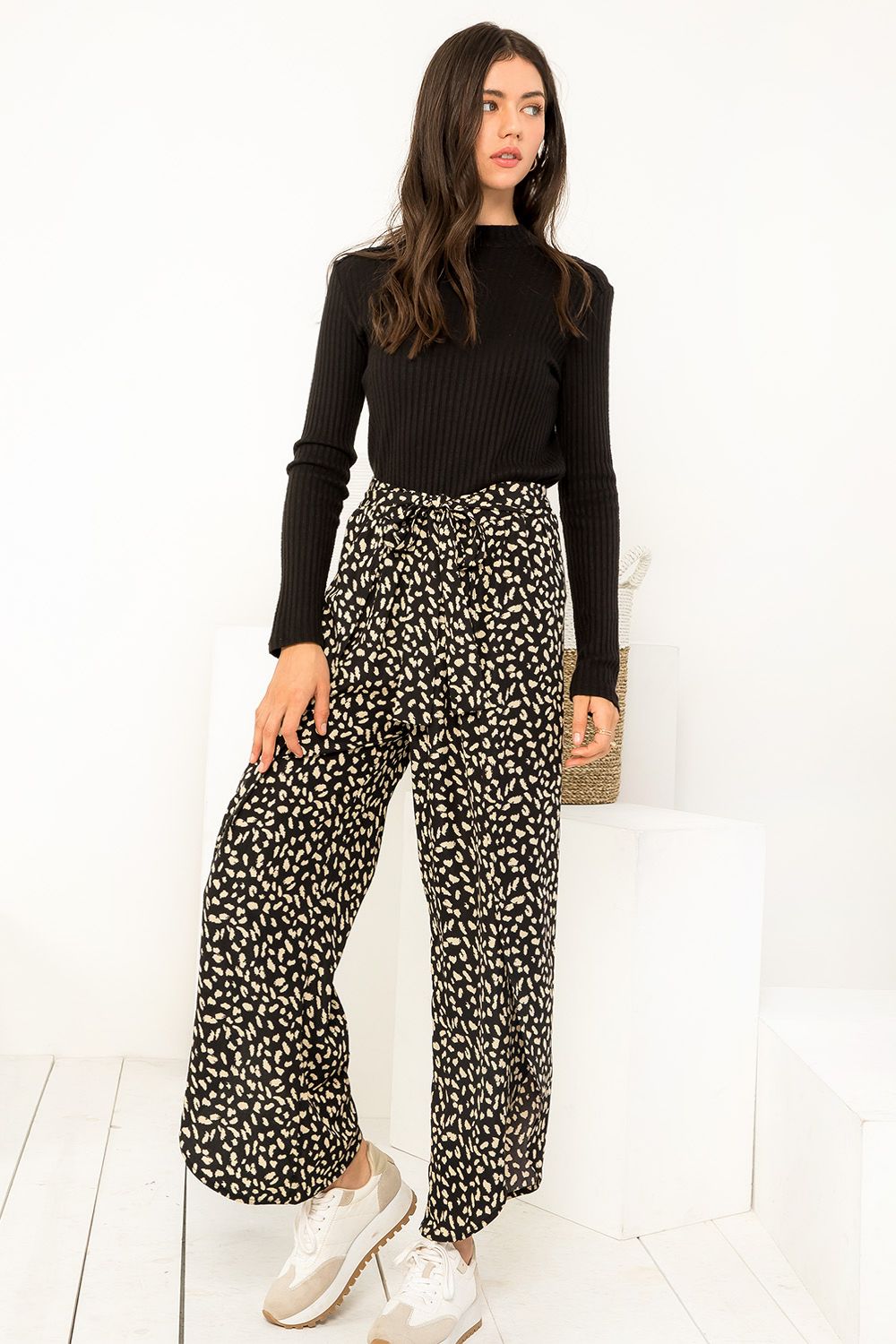 Woman wearing a black top and patterned pants on a white background