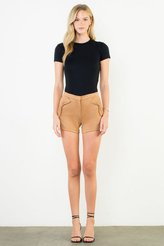 Woman wearing a black t-shirt and tan shorts on a white background