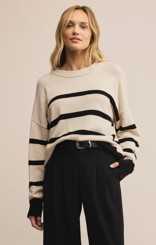 Woman wearing a cream sweater with black stripes on a beige background