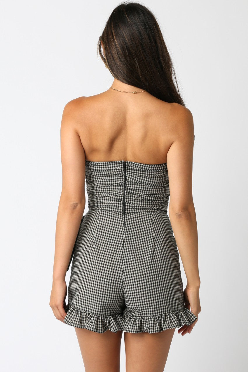 Woman wearing a strapless gingham romper on a white background