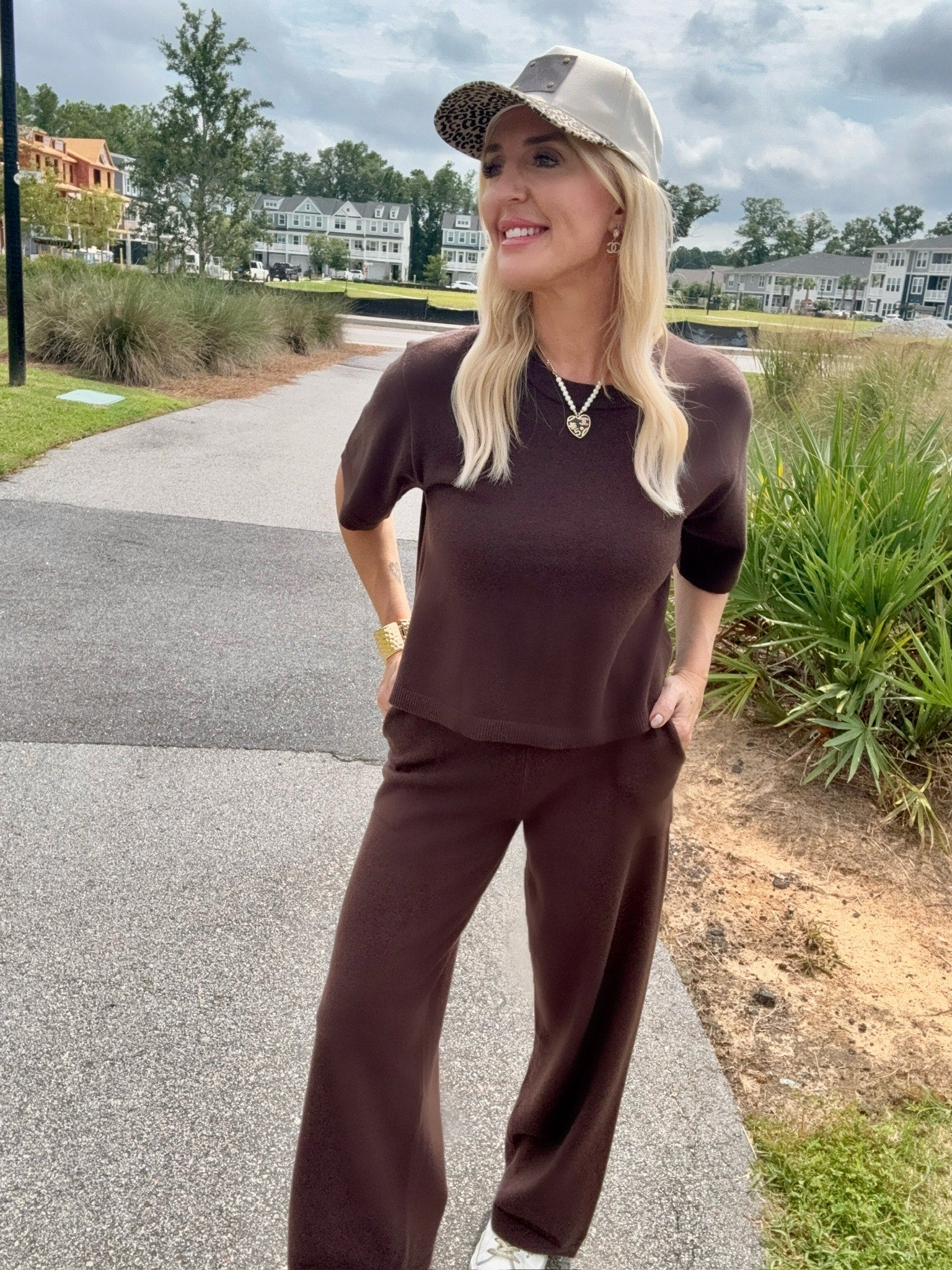 Woman in brown outfit with cap standing on a path outdoors