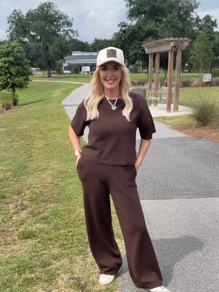 Woman in brown outfit standing on a path in a park