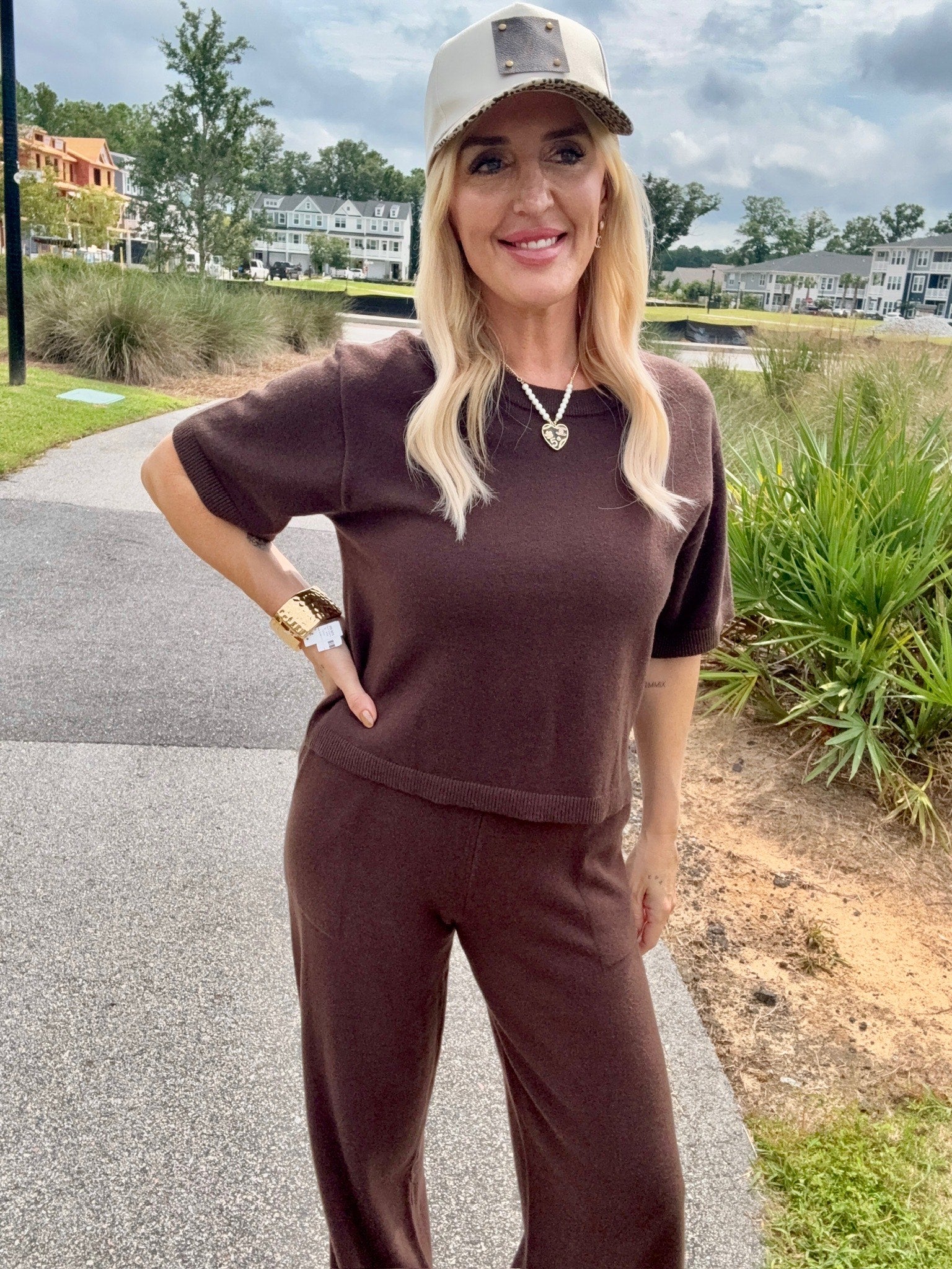 Woman wearing a brown shirt and white cap with leopard print brim outdoors