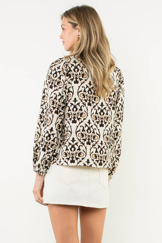 Woman wearing a leopard print top and white skirt on a plain background