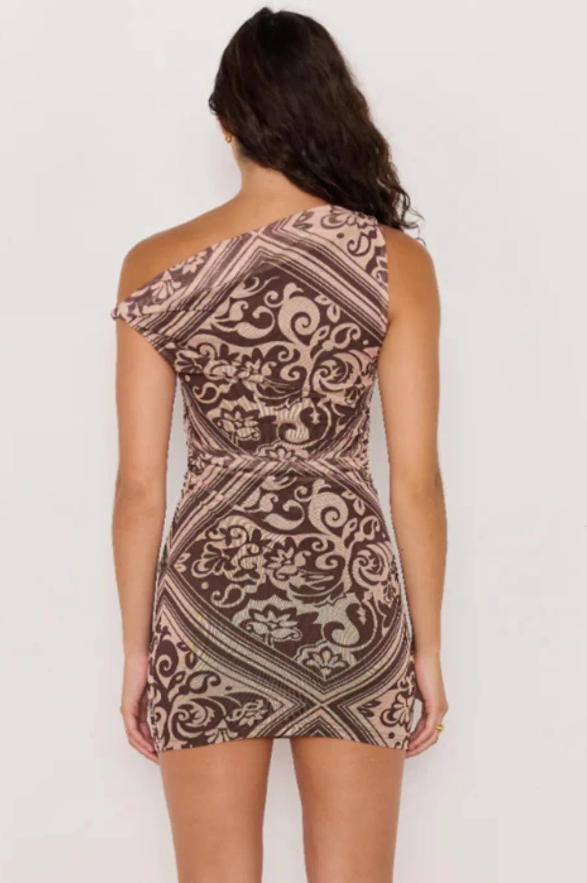 Woman wearing a patterned one-shoulder dress on a white background