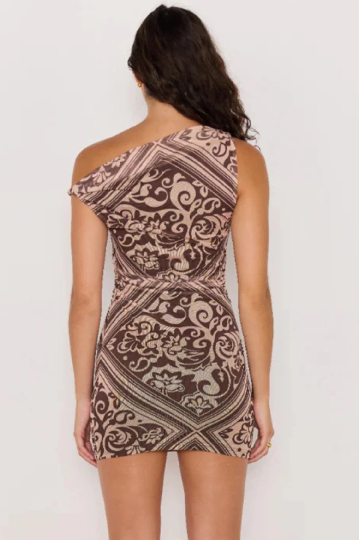 Woman wearing a patterned one-shoulder dress on a white background