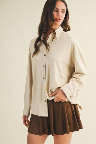 Woman wearing a beige shirt and brown skirt on a plain background