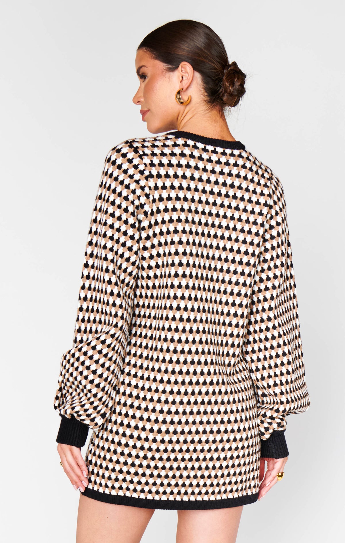 Woman wearing a patterned dress with long sleeves on a plain background