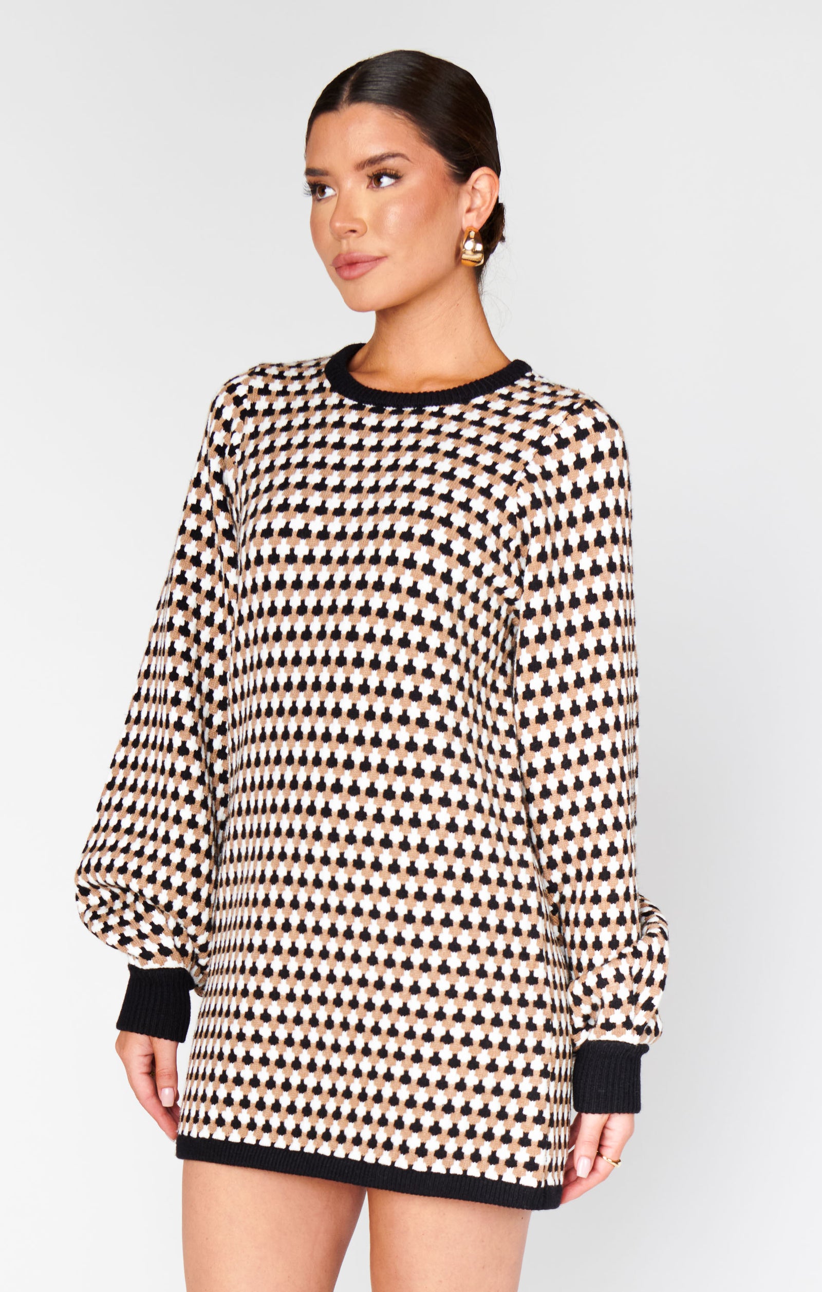 Woman wearing a black and white patterned dress on a plain background