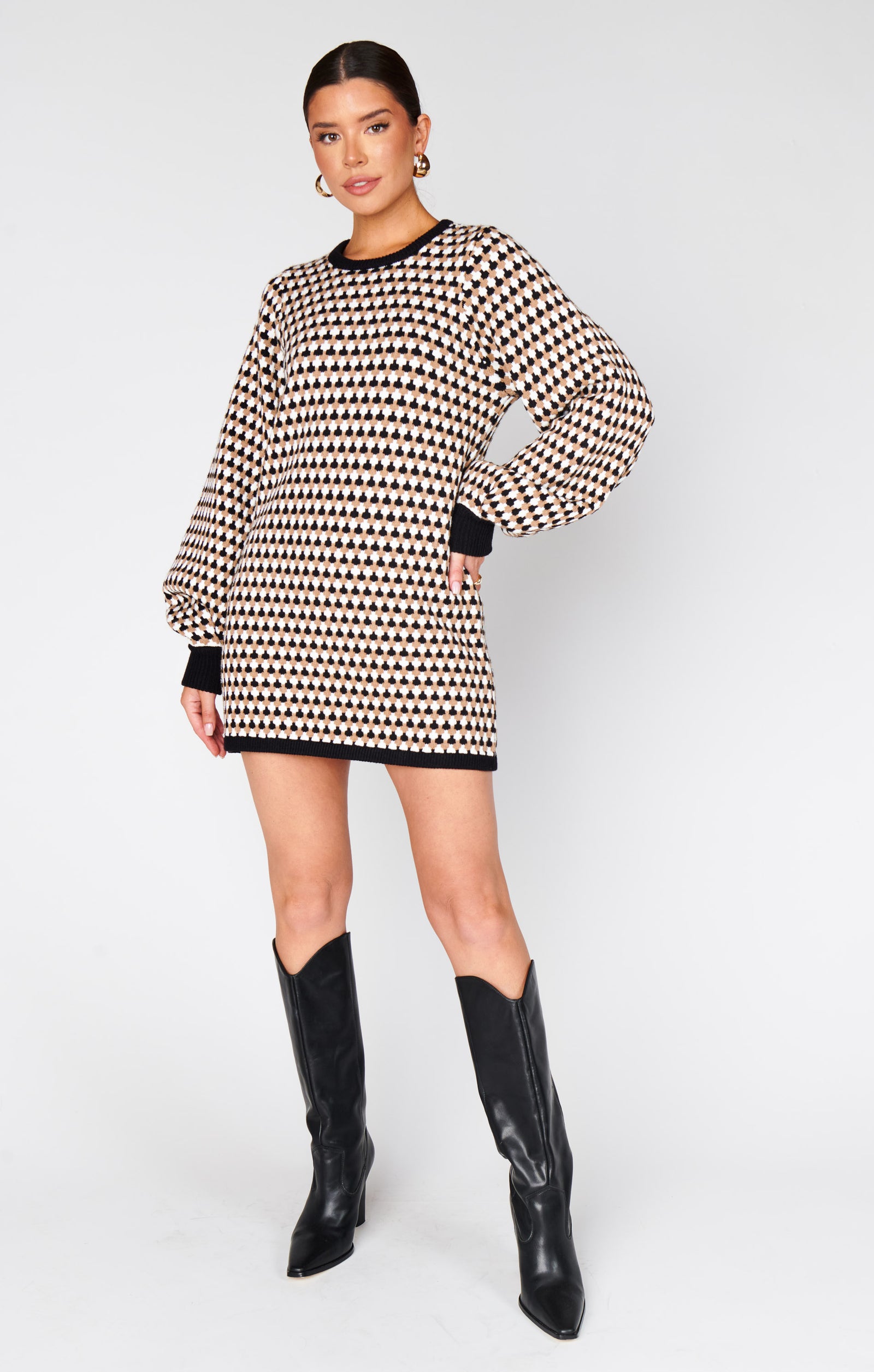 Woman wearing a black and white patterned sweater dress on a plain background