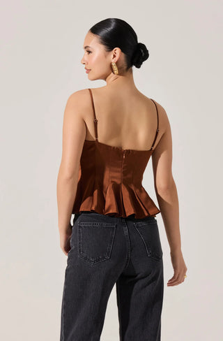 Woman wearing a brown peplum top and black pants on a plain background