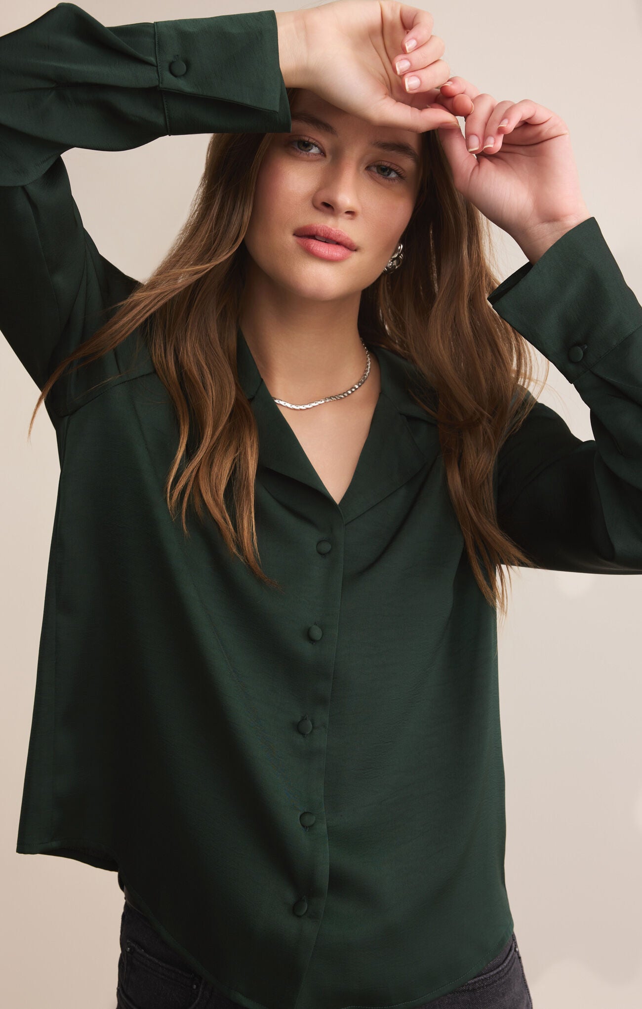 Woman wearing a dark green blouse against a neutral background