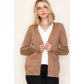 Woman wearing a brown cardigan over a white shirt on a beige background