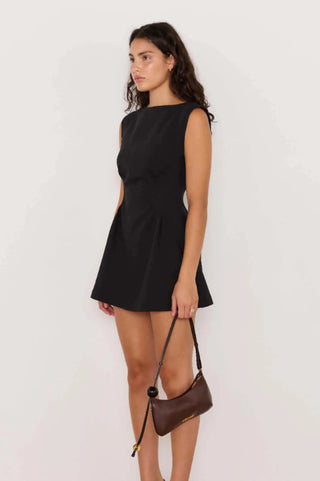 Woman wearing a black dress holding a brown handbag on a white background