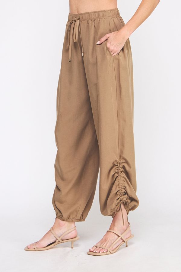 Beige harem pants worn by a person on a white background
