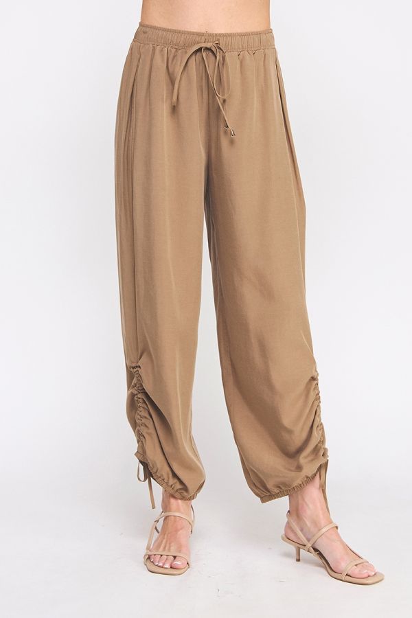 Beige harem pants worn by a person on a white background