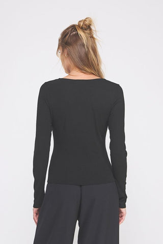 Person wearing a black long-sleeve top and dark pants on a white background