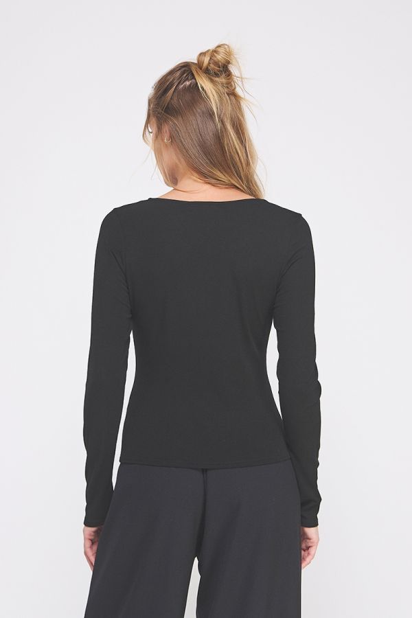 Person wearing a black long-sleeve top and dark pants on a white background