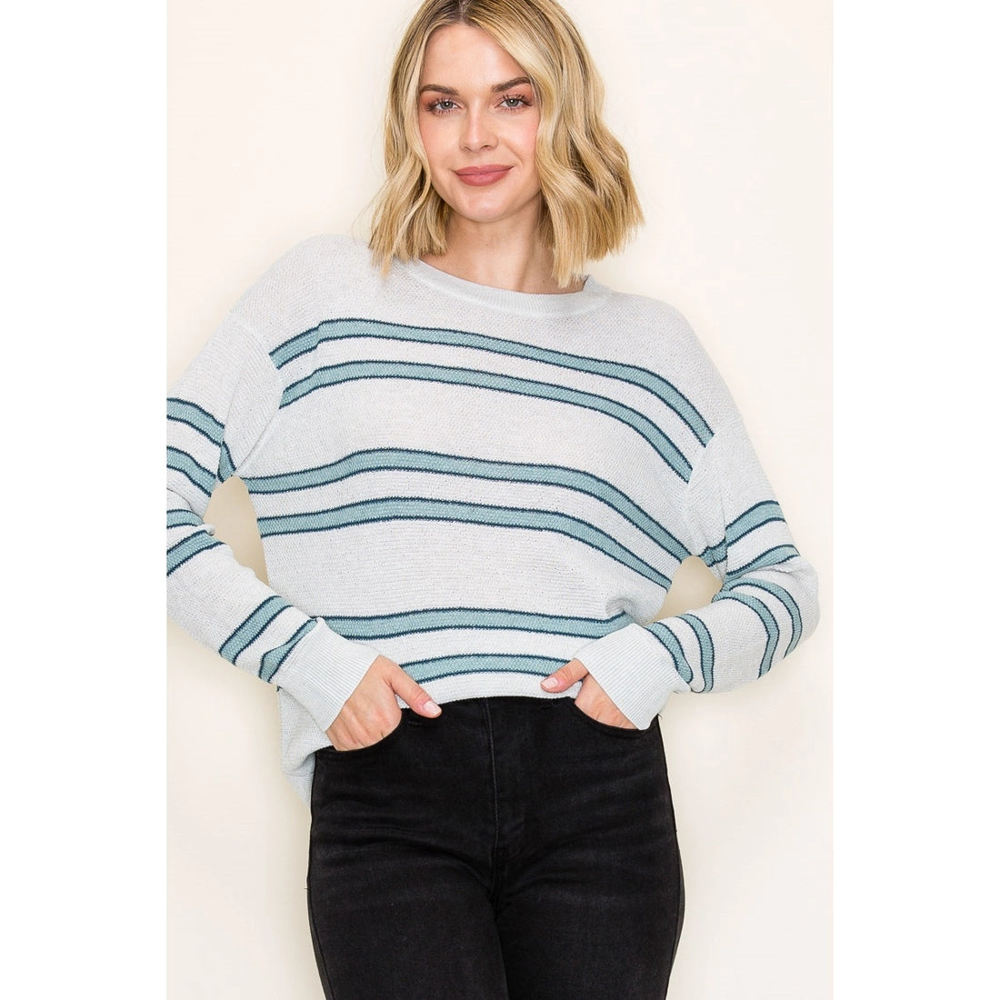 Woman wearing a light blue and white striped sweater against a plain background
