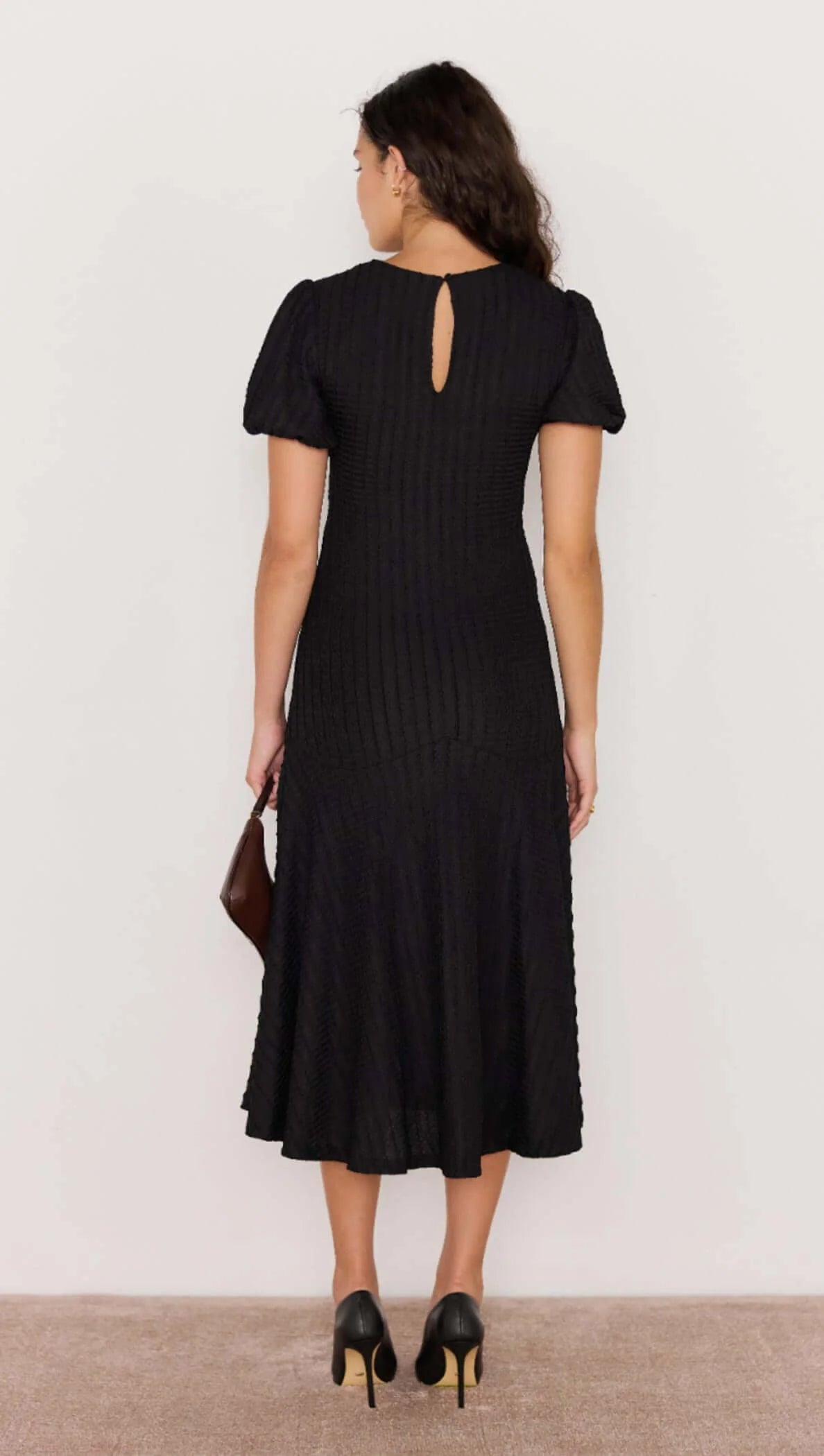 Woman wearing a black dress with a plain background