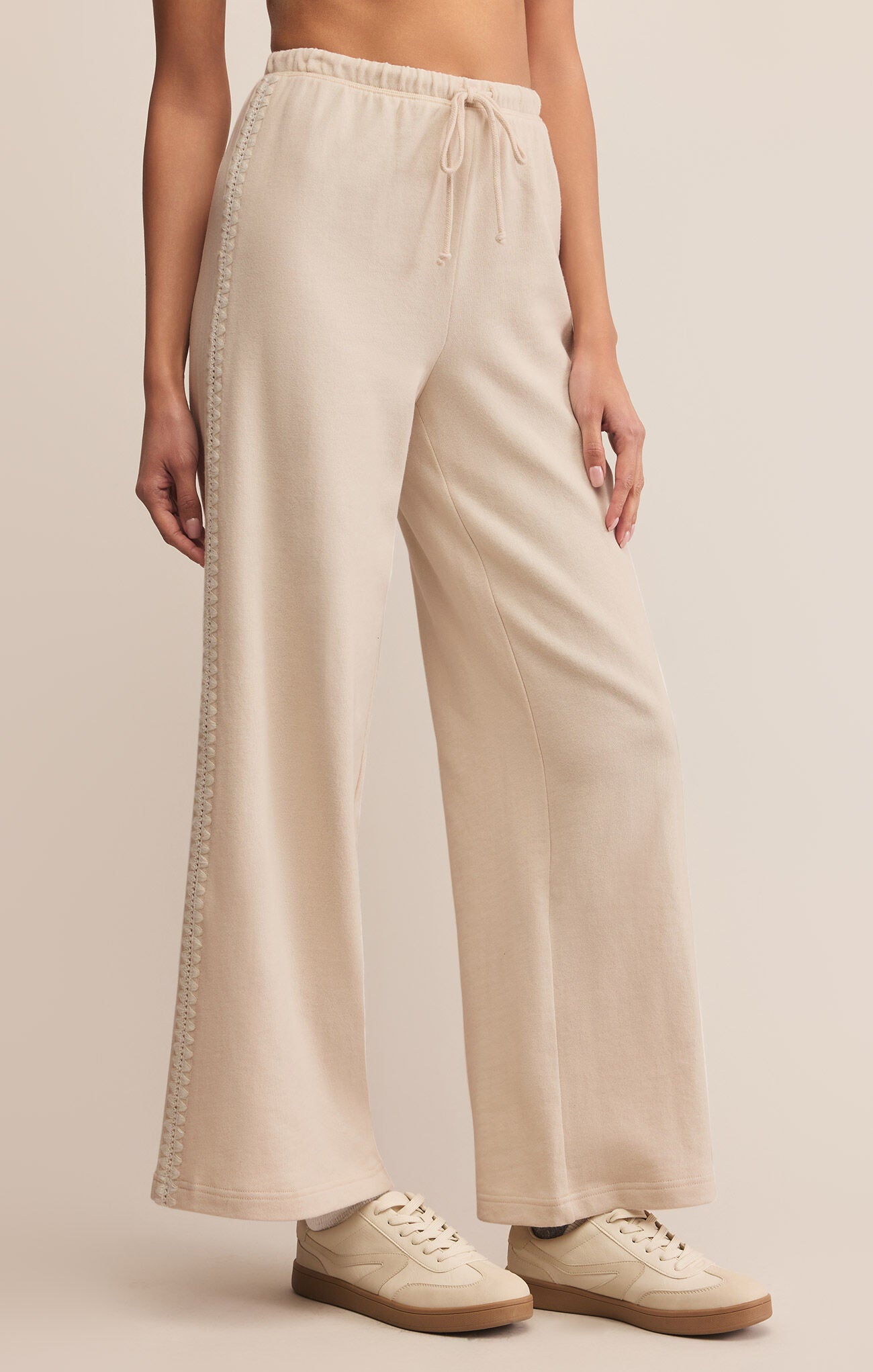 Beige wide-leg pants worn by a person on a beige background