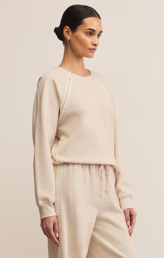 Woman wearing a beige sweater and pants on a plain background