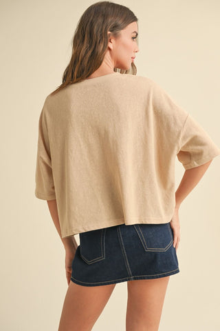 Woman wearing a beige oversized shirt and denim skirt on a beige background