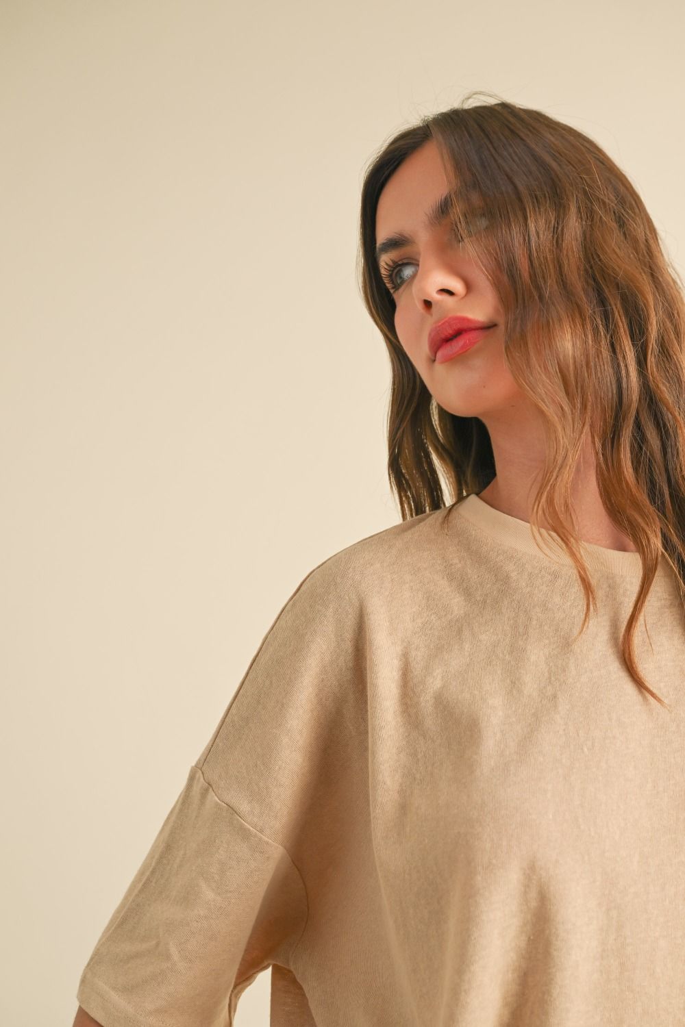 Woman wearing a beige sweater against a plain background