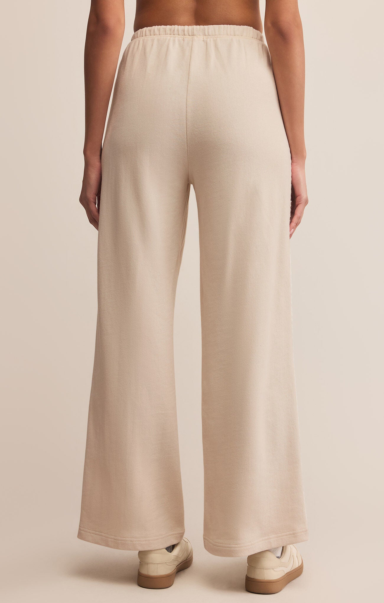 Beige wide-leg pants worn by a person on a beige background