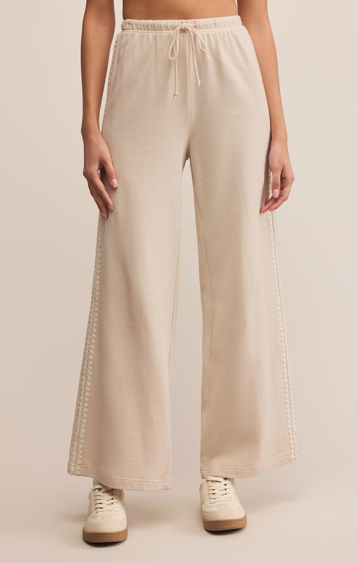 Beige wide-leg pants worn by a person on a beige background