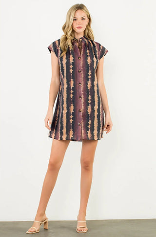 Woman wearing a sleeveless, patterned dress against a white background