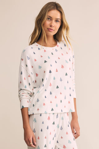 Woman wearing a white pajama set with colorful geometric patterns on a beige background