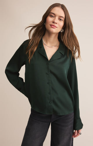 Woman wearing a dark green blouse against a beige background