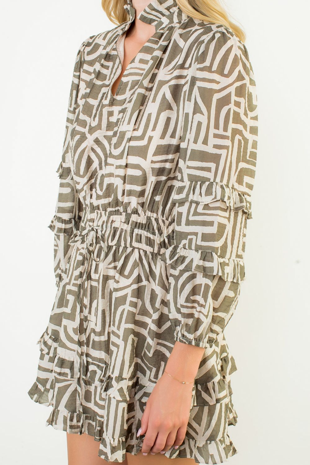 Woman wearing a patterned dress with long sleeves on a white background