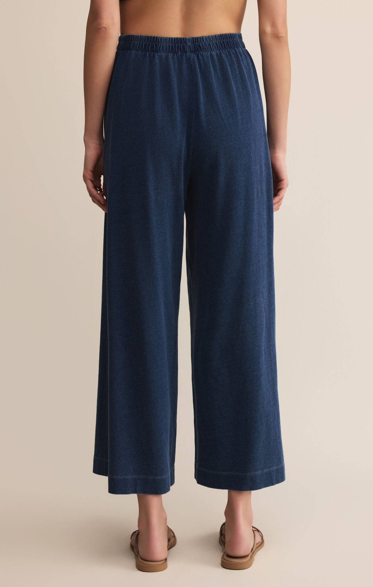 Navy blue wide-leg pants worn by a person on a beige background