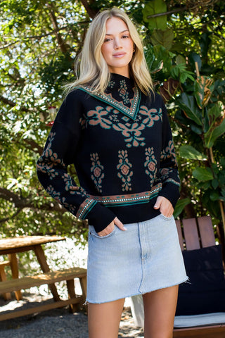 Woman wearing a black patterned sweater and light blue denim skirt outdoors.