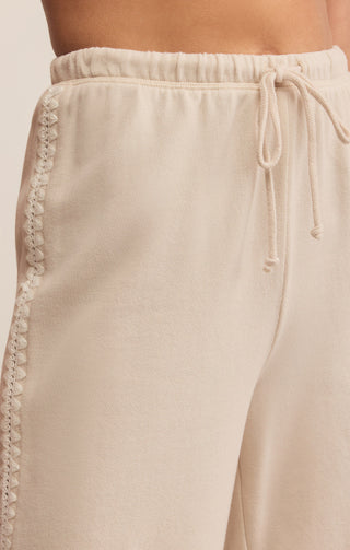 Beige pants with lace trim and drawstring on a light background