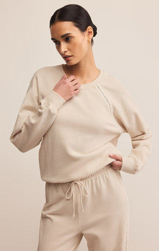 Woman wearing a beige sweater and pants set on a plain background
