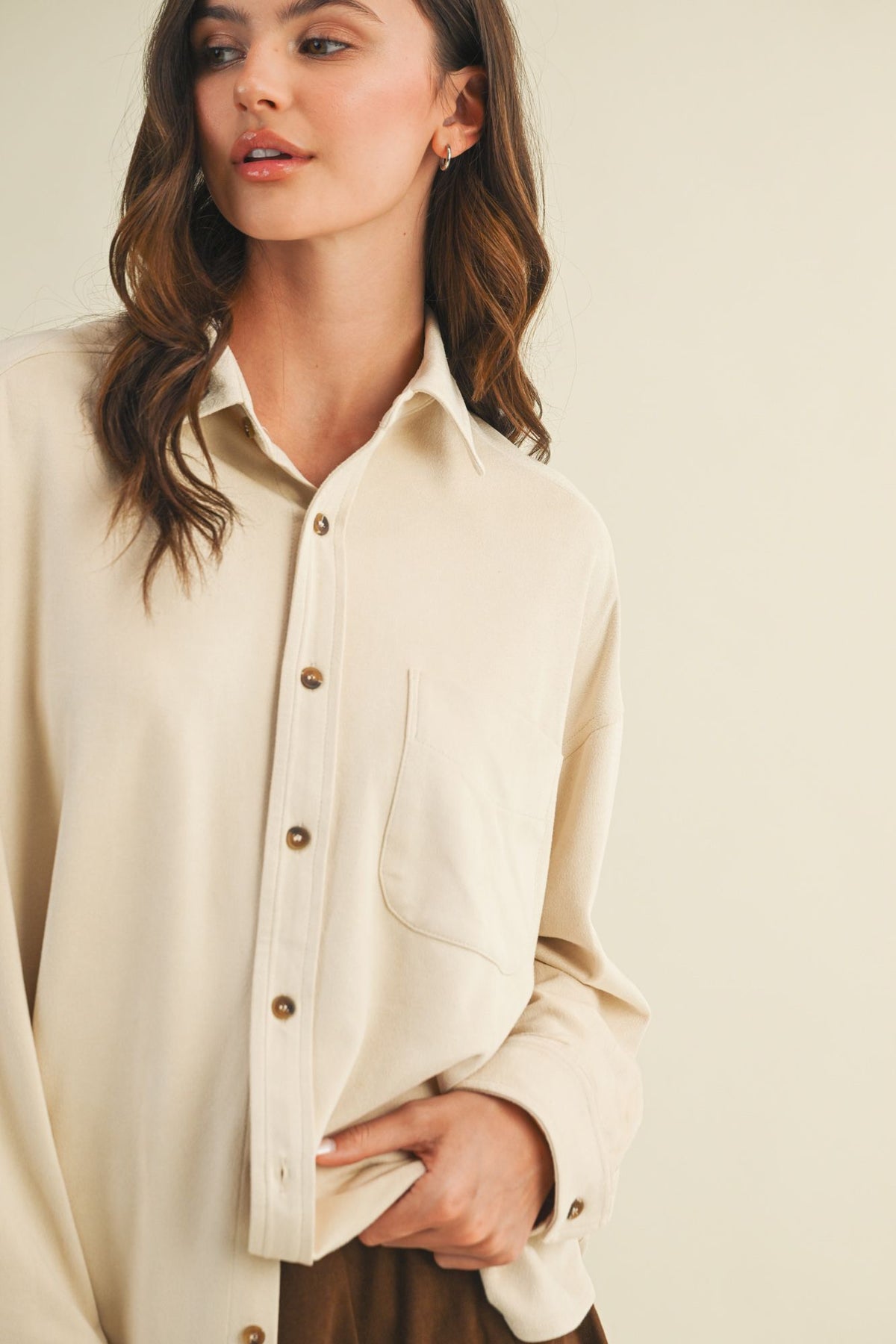 Woman wearing a beige button-up shirt against a plain background