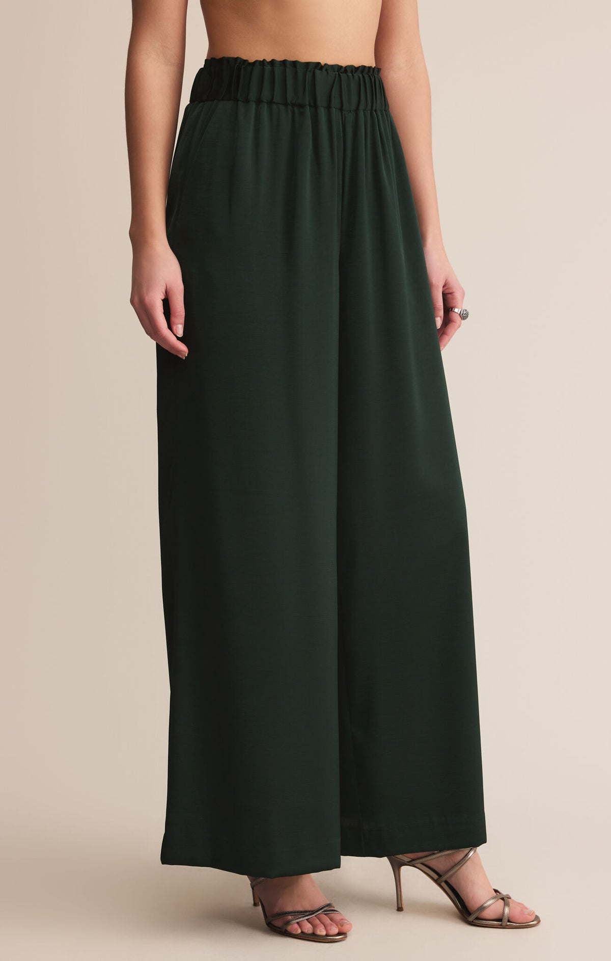 Dark green wide-leg pants worn by a person on a beige background