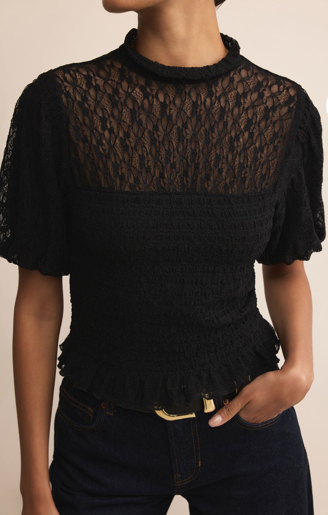 Black lace top worn by a person on a beige background