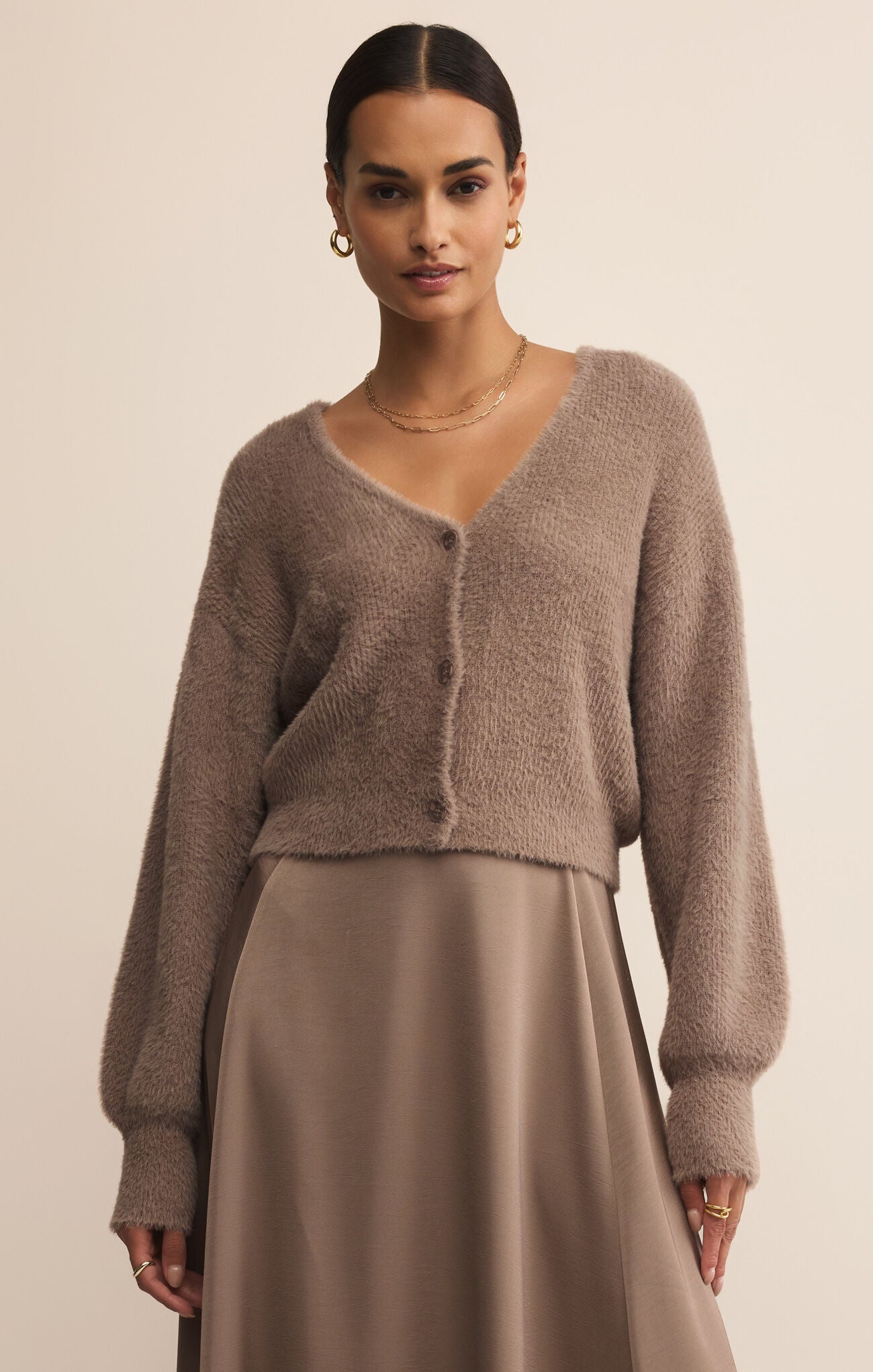 Woman wearing a brown cardigan and skirt against a beige background